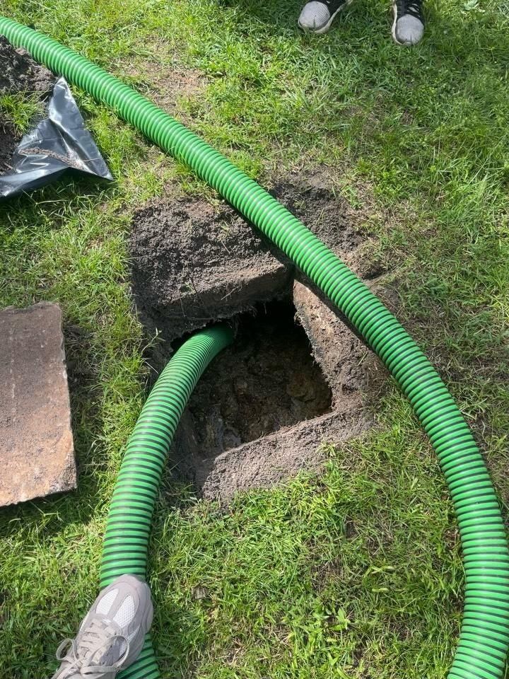 Vacuum hose running into a septic tank access in the lawn