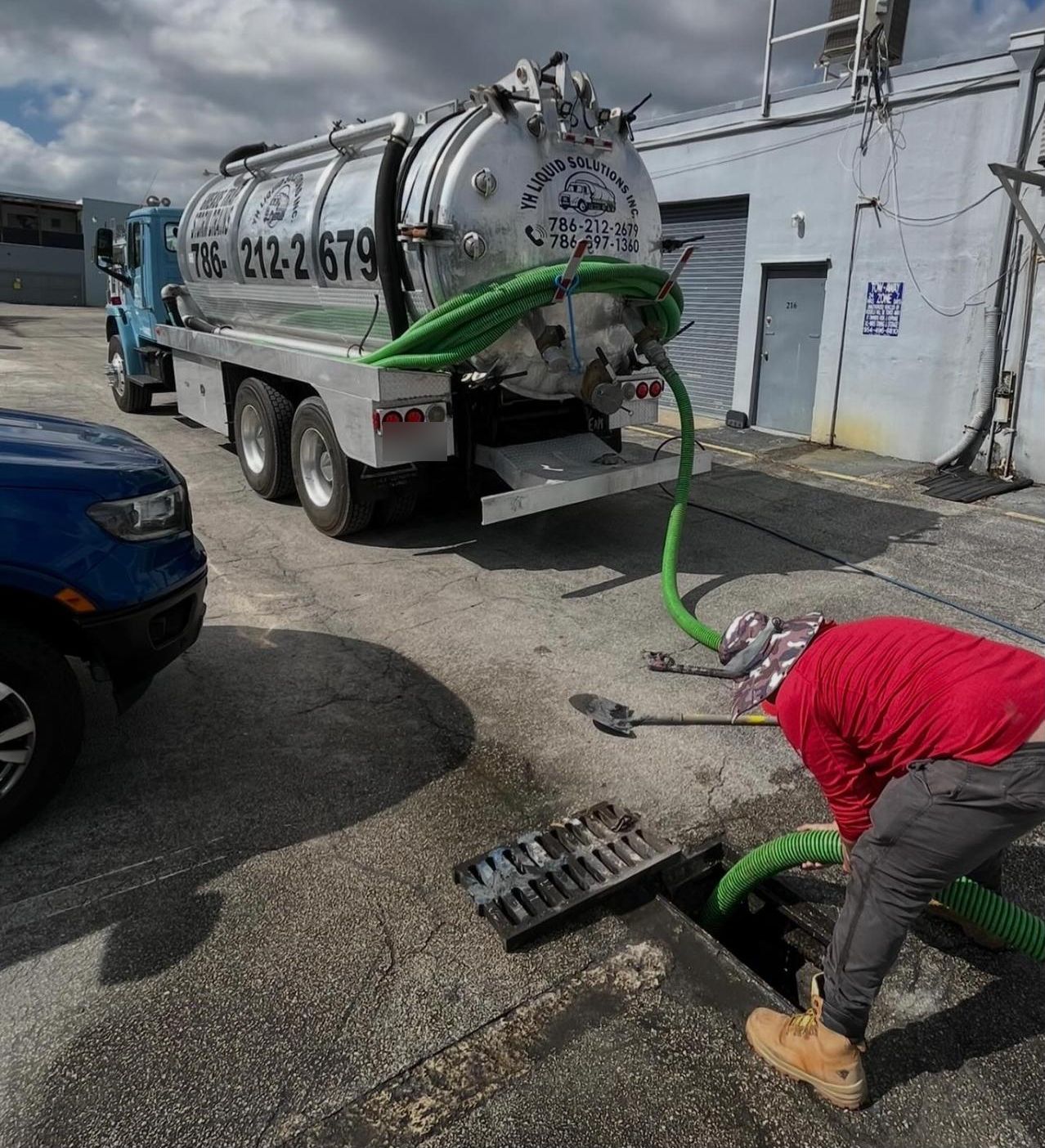 Technician vacuuming out a storm drain catch basin in a parking lot
